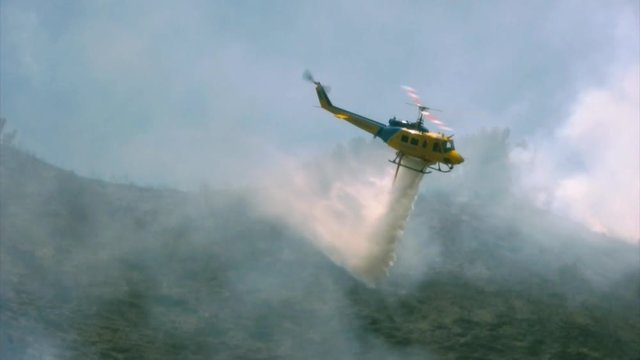A fire rescue helicopter makes a drop over a hillside fire in Southern California. HD 1080.