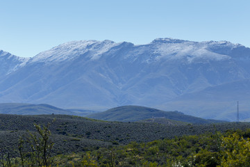 One Tiny Tower on a  Green Landscape with silver snow filled mou