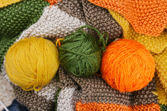 Three yellow, orange and green balls of wool on color wool fabri