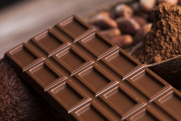 Chocolate bar, candy sweet, cacao beans and powder on wooden bac