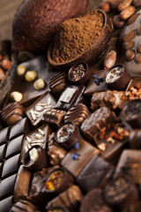 Chocolate bars and pralines on wooden background