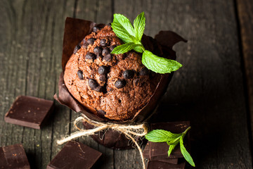 chocolate dark muffin with a leaf of mint on a wooden table with cinnamon, anise, chocolate