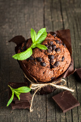 chocolate dark muffin with a leaf of mint on a wooden table with cinnamon, anise, chocolate
