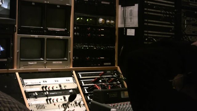 A broadcast news control room with a director taking a break while audio tracks play on LED monitors. HD 1080.