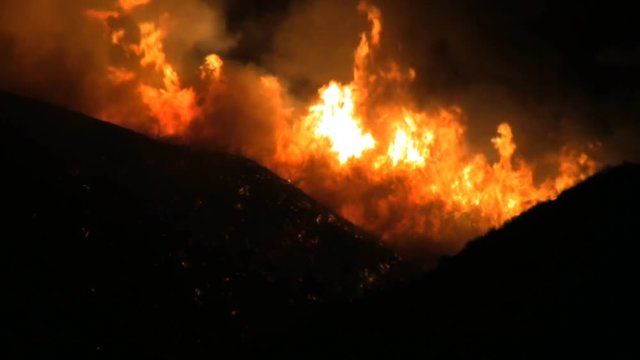 Close up view of wildfires on hillside at night.