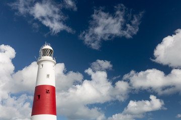 The lighthouse at Portland Bill in Dorset with a cloudy sky behind.