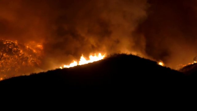 Night shot from the recent fires in Southern California over a silhouette of a hillside. This clip was taken near Magic Mountain in Valencia, CA. HD 1080.