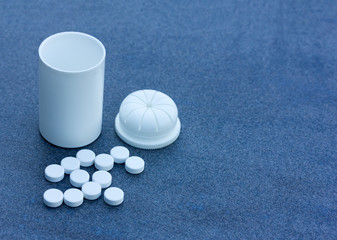 White Pills scattered across a Blue Background and an Open Bottle. Top View Closeup. With Space For...