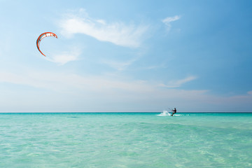 Athlete young man rides a kite on azure water of the Caribbean Sea in hot sunny summer day