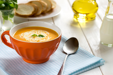 Tasty seasonal pumpkin soup with cream in the orange bowl.