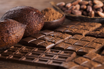 Dark homemade chocolate bars and cocoa pod on wooden