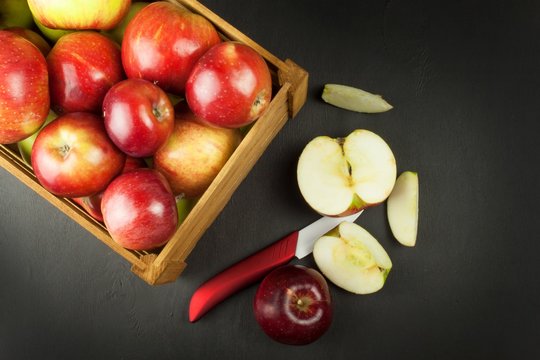 Fresh red autumn apples in farmhouse style wooden crate. Sales of farm products. Advertising for the sale of fruit. Ceramic knife fruit.
