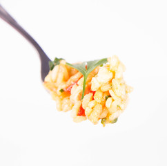 Risotto with chicken, tomatoes, bell pepper, onion, garlic and parsley on a fork on a white background
