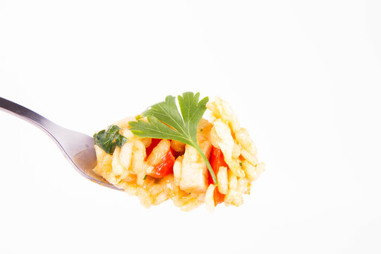 Risotto with chicken, tomatoes, bell pepper, onion, garlic and parsley on a fork on a white background