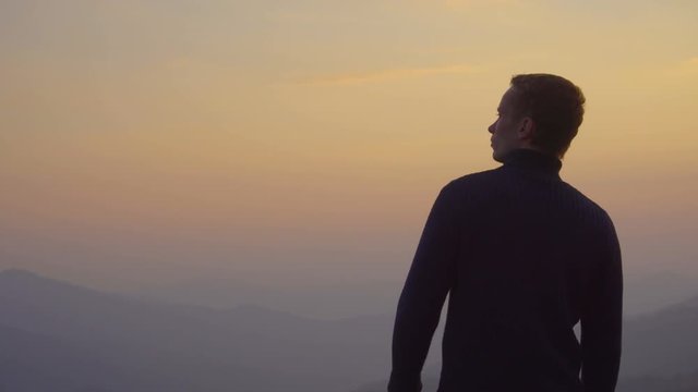 2 in 1 video! The man stand on the top of the mountain against the background of sunset. Real time capture. Wide angle