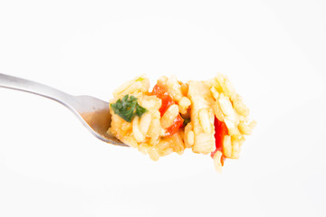 Risotto with chicken, tomatoes, bell pepper, onion, garlic and parsley on a fork on a white background