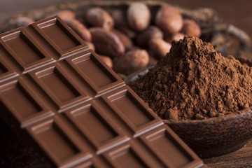 Chocolate bar, candy sweet, cacao beans and powder on wooden bac