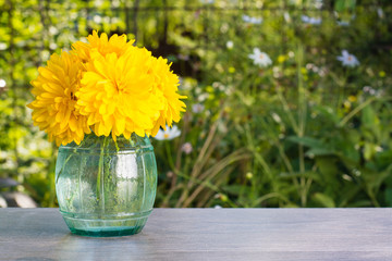 Букет садовых цветов "золотой шар" в вазе на деревянном столе