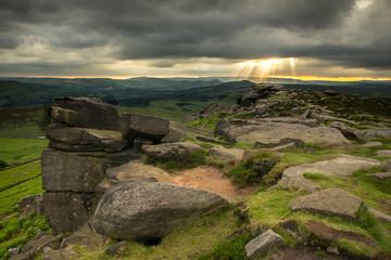 Sun rays breaking through clouds over Stanage Edge
