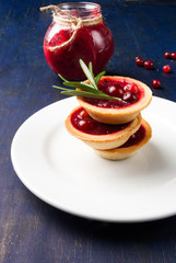 Winter one bite-sized snack or dessert: tartlets with sweet and sour cranberry sauce, decorated with rosemary. 