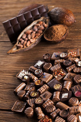 Chocolate bars and pralines on wooden background