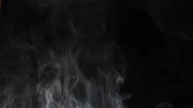 An isolated studio shot of smoke rising over black.