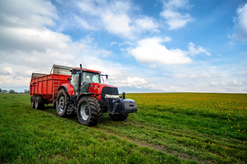 huge tractor in floral spring  field under the blue cloudy sky