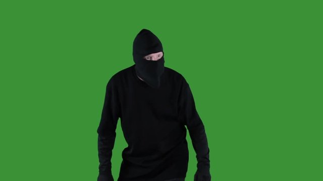 Thief in black ski mask stalking on green screen.