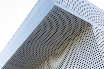 Abstract metallic shape. Close up of a facade made of holed metal plates.
