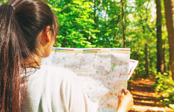 Woman In Reading A Map In The Forest