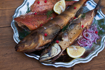 smoked fish mackerel, sea bass and lingcod on metal plate, wooden background
