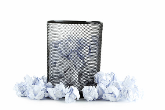 Office trashcan with crumpled paper balls isolated on white