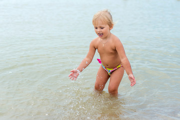 Adorable toddler girl playing with beach toys on white sand beach