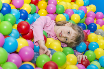 Fototapeta na wymiar Happy children playing and having fun at kindergarten with colorful balls, a child in the pool with balls.