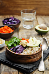 Rice bowl with red cabbage, carrots, avocado, arugula and hummus