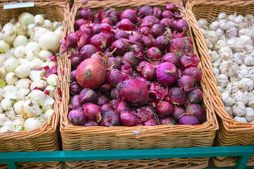 Fresh red onion in wicker tray on shelf in mall