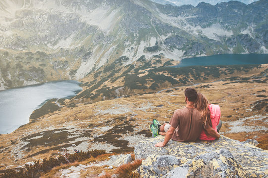Fototapeta A young couple sitting on a rock and enjoying the view