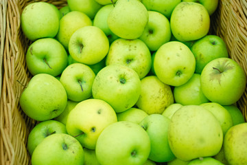 Fresh green apples in wicker tray of a supermarket