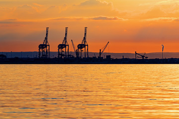 Fototapeta premium Big gantry cranes of a Gdansk shipyard silhouetted by a sunset. Poland.
