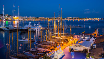 Obraz premium Old Port Vieux Port w mieście Cannes w nocy. Wiele jachtów żaglowych i jachtów motorowych zakotwiczonych podczas regat żeglarskich.