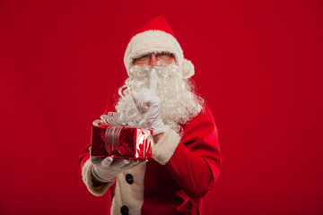 Photo of kind Santa Claus giving xmas present and looking at cam