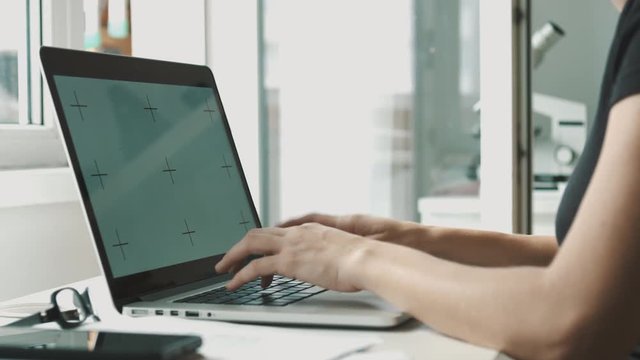 Woman working on laptop at home interier near the window. Hands and fingers on the keyboard close-up