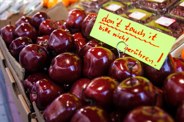 Lots of red-ripe apples in the portable stall at the market in Austria with a hadwritten caution board 