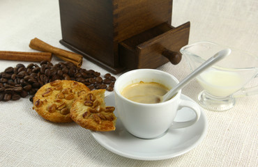 Coffee cup, biscuit, grinder and coffeebeans on table