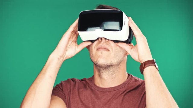Close up shot of a young man wearing virtual reality googles / VR Glasses on green background