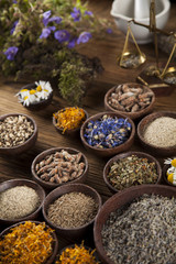 Herbs, berries and flowers with mortar, on wooden table backgrou