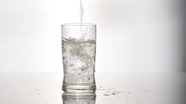 Pouring water in glass on white background