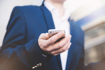 Businessman with telephone in hand and holding a newspaper. Stylish man at the railway station in a blue jacket.