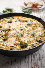 Baked egg frittata with spinach, cheese, broccoli, red potatoes, bacon, milk, and spinach side vertical view
