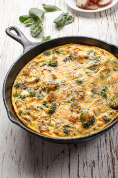 Baked egg frittata with spinach, cheese, broccoli, red potatoes, bacon, milk, and spinach angled view close up